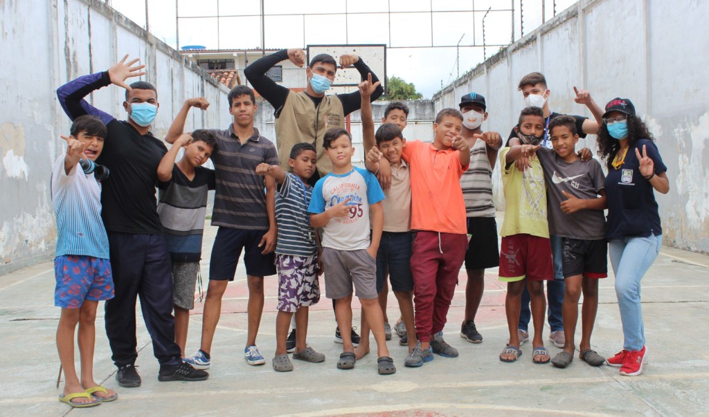 A group of children and teens pose together in an outdoor community recreation area in Venezuela.