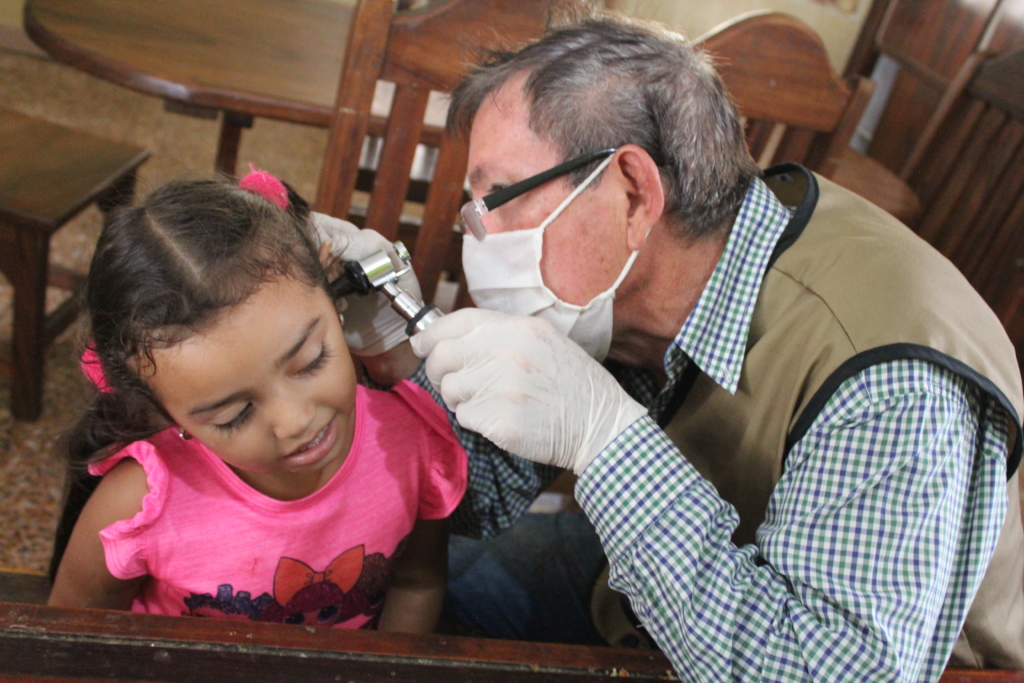 A doctor examines a young girl’s ear during a medical visit in Venezuela.