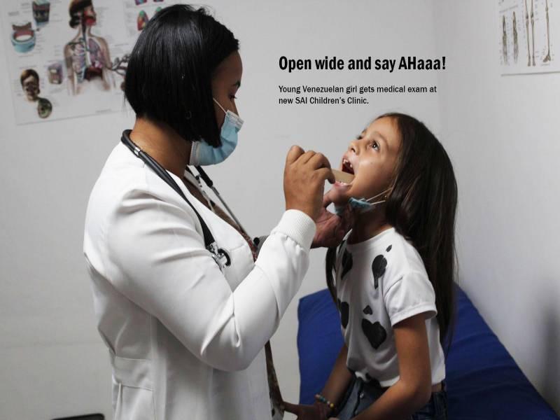A doctor examines a young girl’s throat during a medical checkup at SAI Medical Clinic.