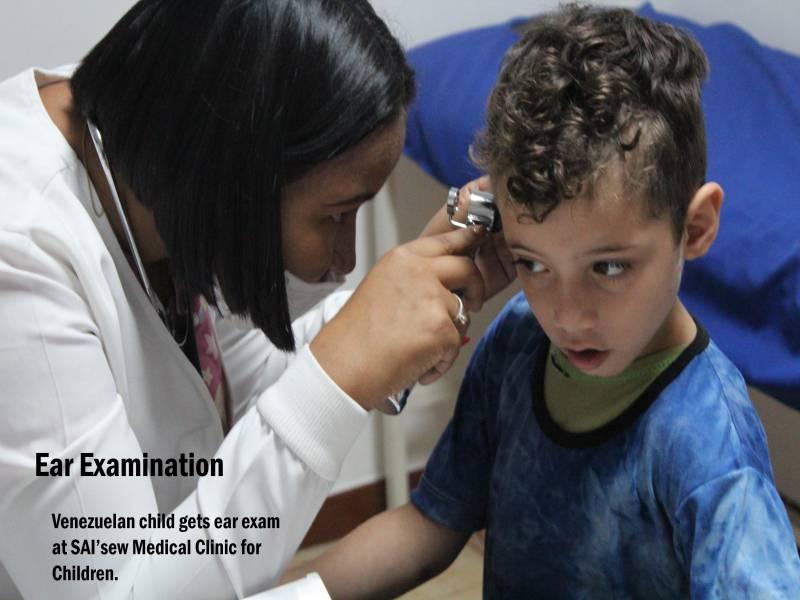 A doctor performs an ear examination on a young child at SAI Medical Clinic in Venezuela.