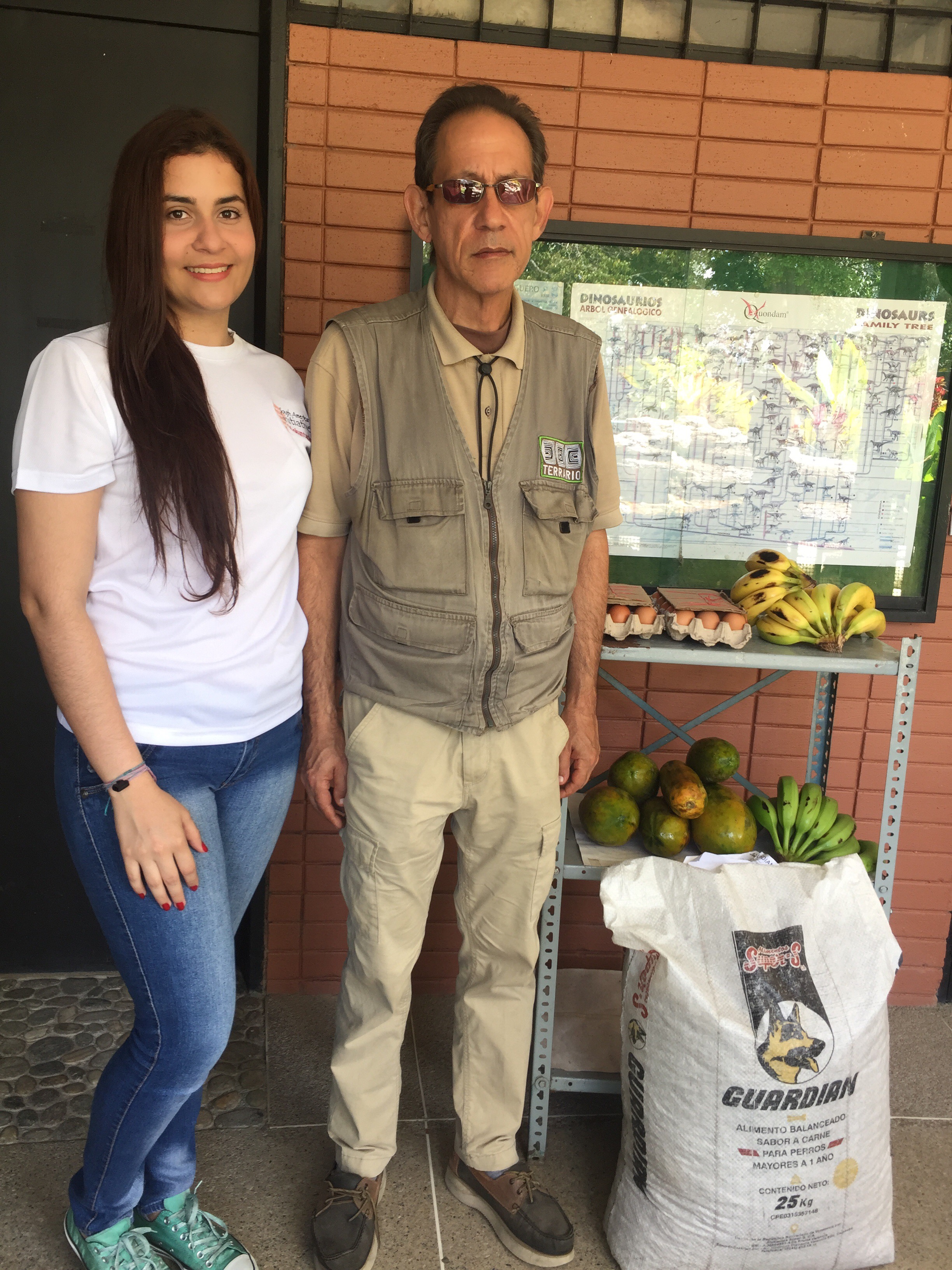 SAI volunteer standing with local zoo staff beside donated food supplies for animals in Venezuela.