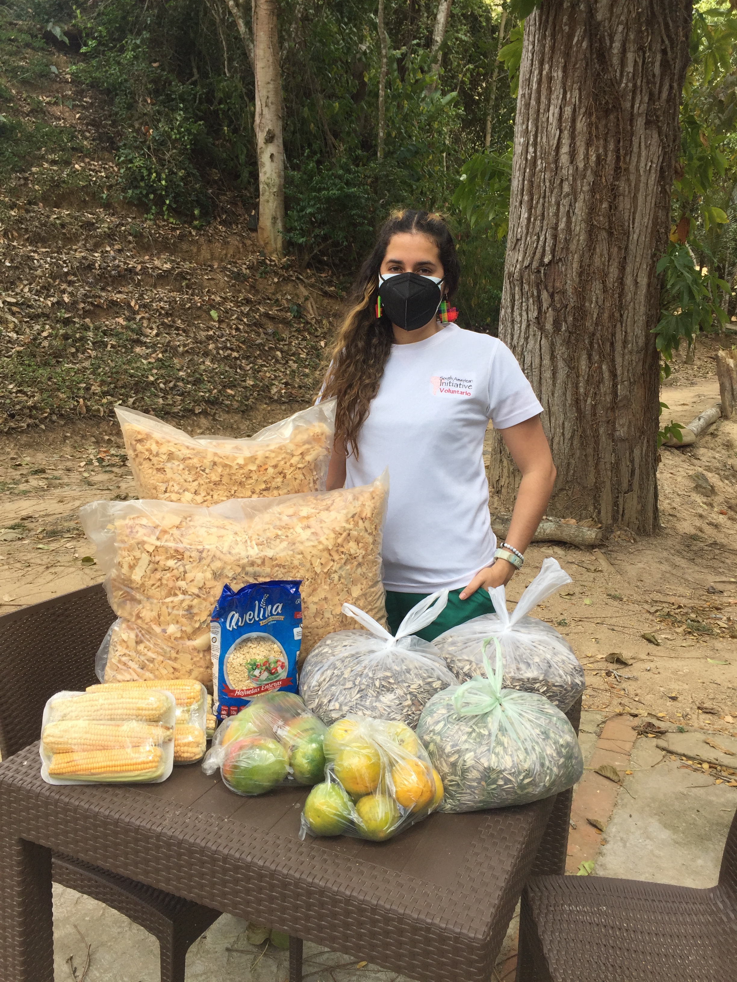 SAI volunteer standing beside food and supplies prepared for zoo animals in Venezuela.