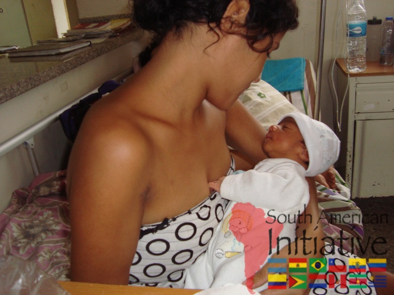 A mother holding her newborn baby in a hospital room during a humanitarian support visit by SAI.