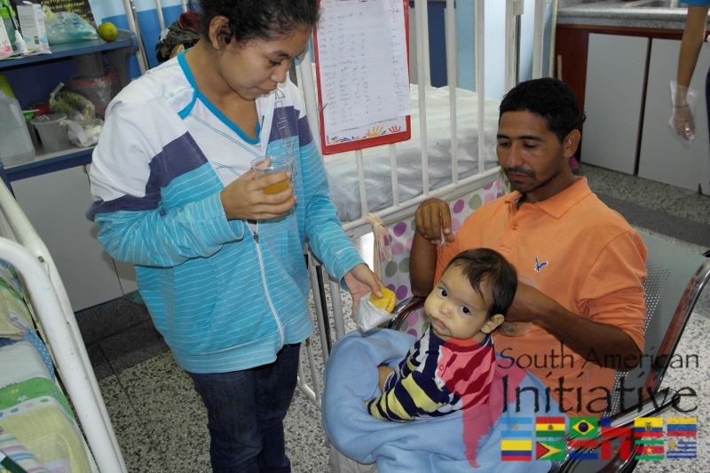 A family with a young child receiving food and support in a pediatric hospital ward in Venezuela.