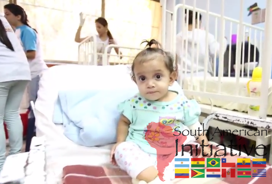 A young child sitting on a hospital bed in a pediatric ward supported by SAI in Venezuela.