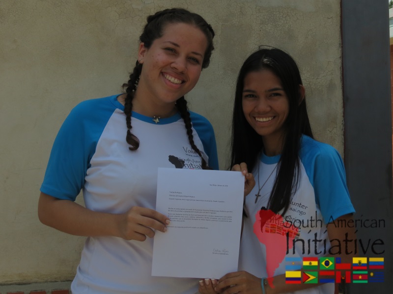 Two SAI volunteers smiling and holding a letter of recognition during a humanitarian mission in Venezuela.