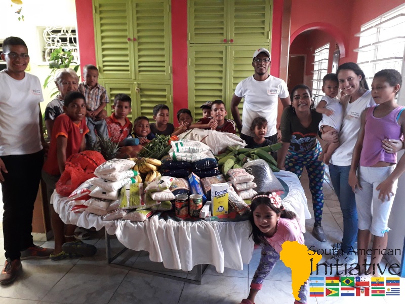 A family standing around a table filled with donated groceries and supplies provided through SAI in Venezuela.