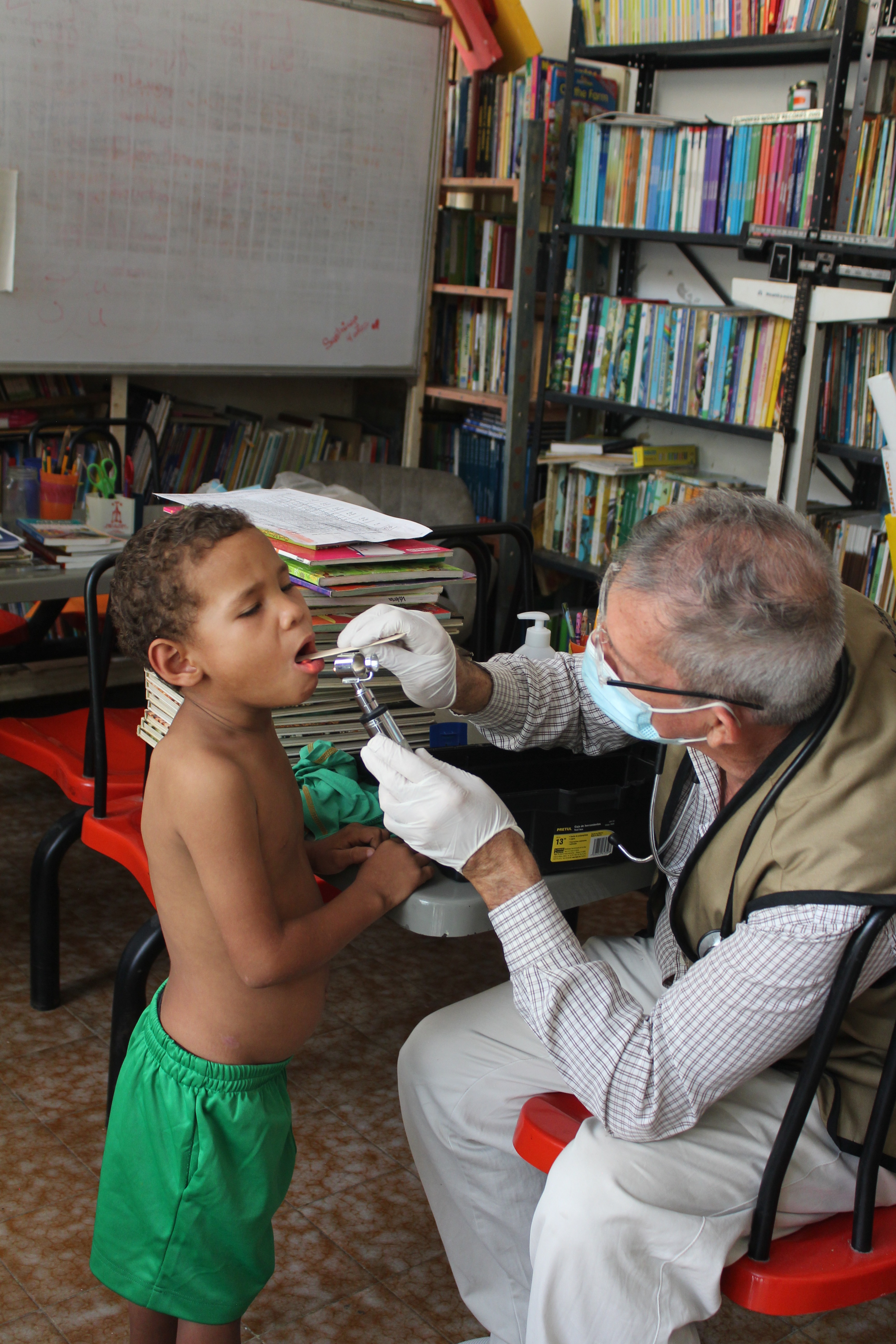 A doctor examining a young child during a medical visit supported by SAI in Venezuela.