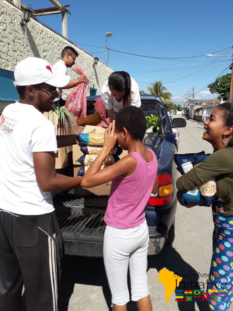 SAI volunteers unloading food and supplies from a truck to distribute to families in a Venezuelan neighborhood.