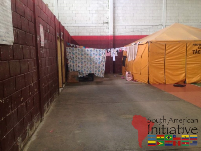 A shelter area with temporary tents and privacy partitions inside an emergency refuge for Venezuela refugees provided by SAI