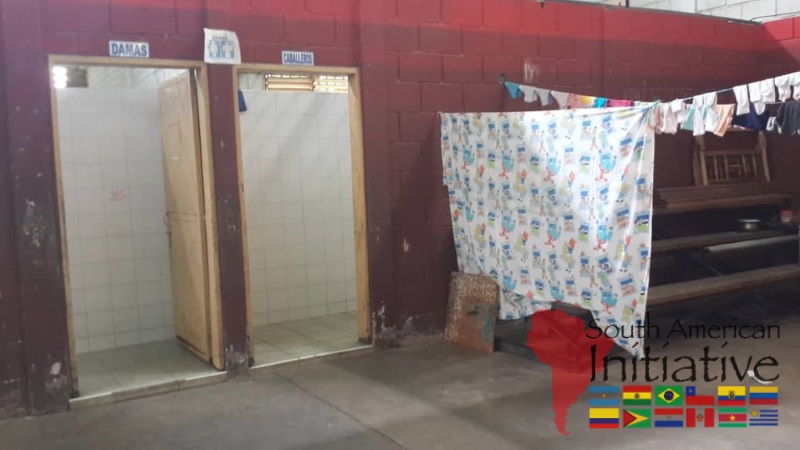 Restroom facilities and a privacy area inside a shelter space for displaced families from Venezuela.