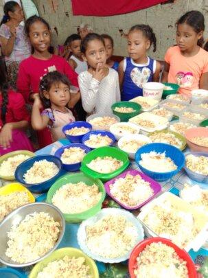 SAI Celebrates and Supports Orphans in Venezuela with Nourishing Meals SAI (South American Initiative), a dedicated non-profit organization, brings joy and nourishment to orphaned children in Venezuela. In this image, children gather around a table filled with bowls of food, enjoying a communal meal provided by SAI. A decorated cake featuring the word "Feliz" suggests a festive celebration, reinforcing SAI’s mission to improve the lives of vulnerable children through free meals, medical care, and educational support. Through donations and volunteer efforts, SAI continues to bring hope and sustenance to orphanages across the country.