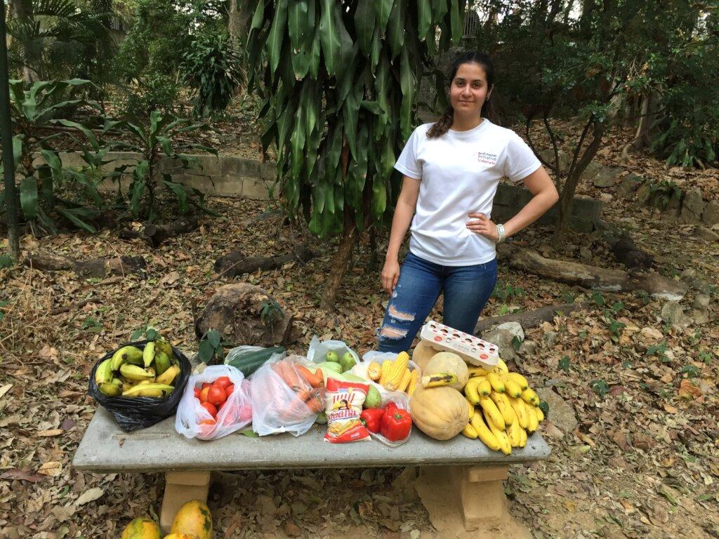 SAI Volunteers Prepare Nutritional Support for Rescued Animals in Venezuela SAI (South American Initiative), a dedicated non-profit in Venezuela, ensures that rescued animals receive essential nourishment tailored to their dietary needs. This image features a carefully arranged selection of fresh produce displayed on a stone bench in an outdoor setting, surrounded by lush trees and foliage. The assortment includes bananas, papayas, melons, tomatoes, carrots, corn, bell peppers, and packaged snacks, highlighting the organization’s commitment to providing balanced, nutritious meals. Through the dedication of volunteers and the generosity of donors, SAI continues to secure vital food resources, supporting the health and recovery of vulnerable animals under its care.