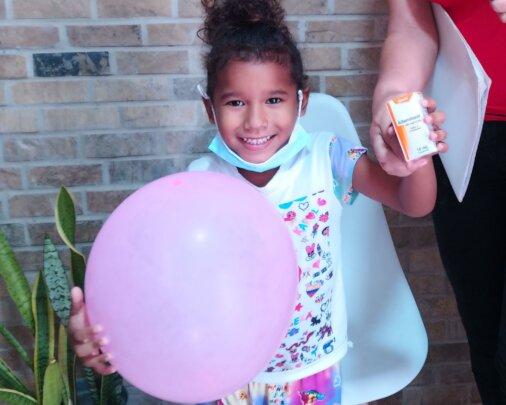 Happy Little Girl Receiving Free Medicine at SAI Clinic in Venezuela